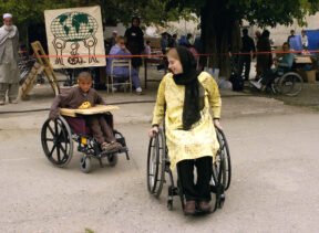 Jenny Smith in wheelchair training middle-eastern child how to use their wheelchair