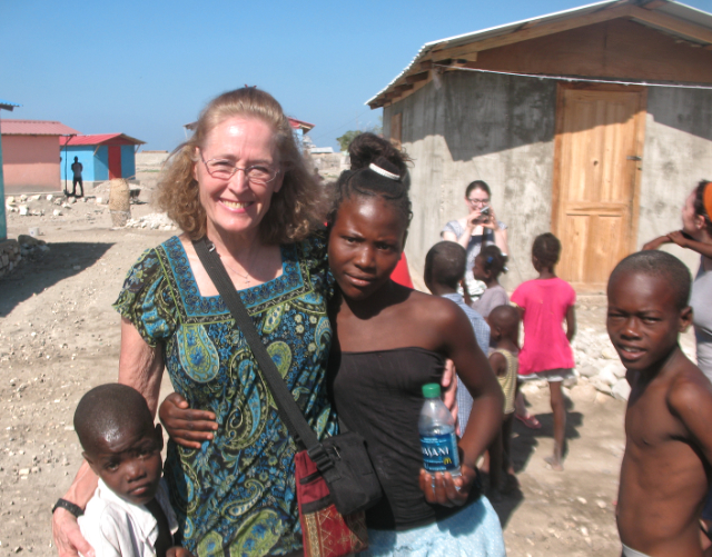 Sharon McElwain standing with African children in front of small hut