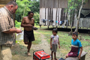 Caucasian man in jungle village with one indigenous man and two children