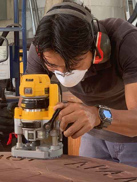Indigenous young man wearing a dust mask and ear protectors works with a router