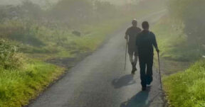two men walk along a country road.